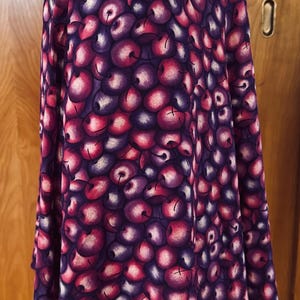 Peut inclure: Jupe trap&egrave;ze orn&eacute;e d'un motif de cerises vives dans les tons de violet, rose et blanc. La jupe est faite d'un tissu fluide et a une taille haute. La jupe mesure environ 61 cm de long.