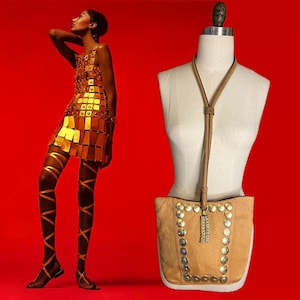 May include: A tan leather shoulder bag with a long strap and gold-toned metal accents. The bag has a flap closure and a tassel detail.