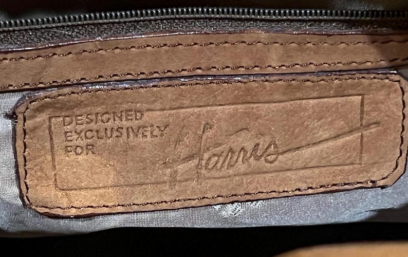 May include: Close-up of a brown leather label with the text "DESIGNED EXCLUSIVELY FOR Harris" embossed in the leather.
