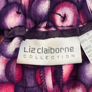 Peut inclure: Gros plan sur un v&ecirc;tement avec un motif vibrant de fruits violets et roses. L'&eacute;tiquette indique "Liz Claiborne Collection". Le tissu semble &ecirc;tre de la soie. Le v&ecirc;tement est de taille 8.