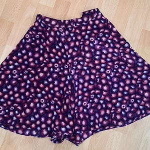 Peut inclure: Jupe &eacute;vas&eacute;e orn&eacute;e d'un motif r&eacute;p&eacute;titif d'orbes violets et roses. La jupe a une taille haute et une forme ample. Le tissu semble l&eacute;ger, adapt&eacute; aux temp&eacute;ratures plus chaudes. Le design de la jupe est accrocheur.