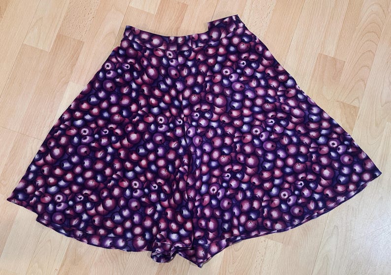 Peut inclure: Jupe &eacute;vas&eacute;e orn&eacute;e d'un motif r&eacute;p&eacute;titif d'orbes violets et roses. La jupe a une taille haute et une forme ample. Le tissu semble l&eacute;ger, adapt&eacute; aux temp&eacute;ratures plus chaudes. Le design de la jupe est accrocheur.