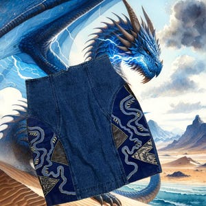 May include: A denim skirt with a blue and gold embroidered design. The skirt is a dark blue wash and has a high waist. The embroidery is on the sides of the skirt and features a swirling pattern.
