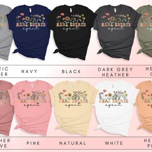 May include: Ten different colour t-shirts with the text "REAL ESTATE agent" and a floral design. The colours are athletic heather, navy, black, dark grey heather, heather olive, heather mauve, pink, natural, white, and heather peach.