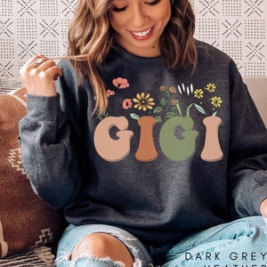 May include: Dark grey heather sweatshirt with the word "GIGI" in colorful letters with flowers growing out of the letters.