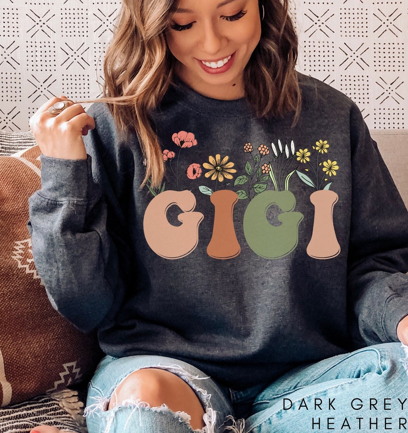May include: Dark grey heather sweatshirt with the word "GIGI" in colorful letters with flowers growing out of the letters.