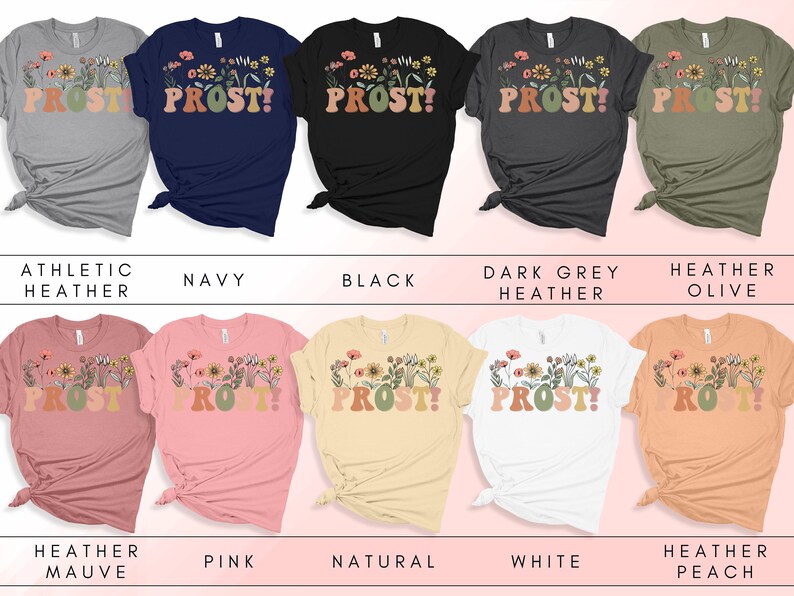 K&ouml;nnte beinhalten: Eine Sammlung von T-Shirts mit einem floralen Design und dem Text "PROST!" in einer Retro-Schriftart. Die Shirts sind in verschiedenen Farben erh&auml;ltlich, darunter Sport-Heather, Marine, Schwarz, Dunkelgrau-Heather, Heather Olive, Heather Mauve, Pink, Natur, Wei&szlig; und Heather Peach.