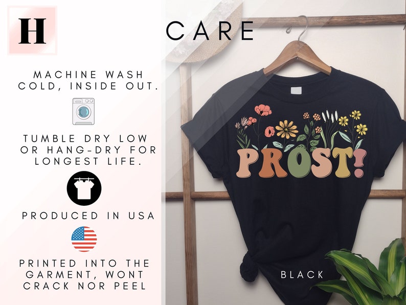 K&ouml;nnte beinhalten: Schwarzes T-Shirt mit floralem Design und dem Aufdruck "PROST!" auf der Vorderseite. Das Shirt ist in den USA hergestellt und maschinenwaschbar.