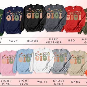 May include: A set of ten sweatshirts in various colors featuring the word "Gigi" with floral accents. The sweatshirts are available in colors such as forest green, navy, black, dark heather, red, military green, ash, light pink, light blue, white, sport grey, sand, and orange.