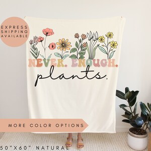 May include: A white throw blanket with a floral design and the text "NEVER. ENOUGH. plants." in colorful retro lettering. The blanket is 50 inches by 60 inches.