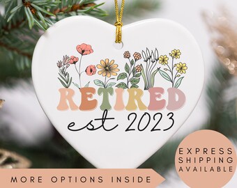 May include: White heart-shaped ceramic ornament with a floral design and the text "Retired est 2023".