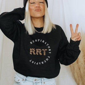 May include: A black sweatshirt with a white circle graphic that says "Respiratory Therapist" with the letters "RT" in leopard print.