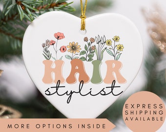 May include: White ceramic heart-shaped ornament with a floral design and the text "HAIR stylist".