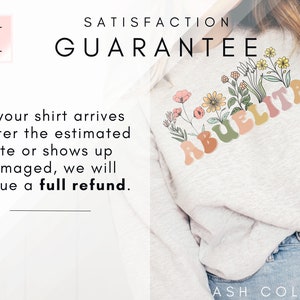 May include: A light gray sweatshirt with the word "Abuelita" in colorful, retro-style letters. The letters are surrounded by a floral design with pink, yellow, and green flowers. The text "Satisfaction Guarantee" is at the top of the image. The text "If your shirt arrives after the estimated date or shows up damaged, we will issue a full refund." is at the bottom of the image. The text "ASH COLOR" is at the bottom right of the image.