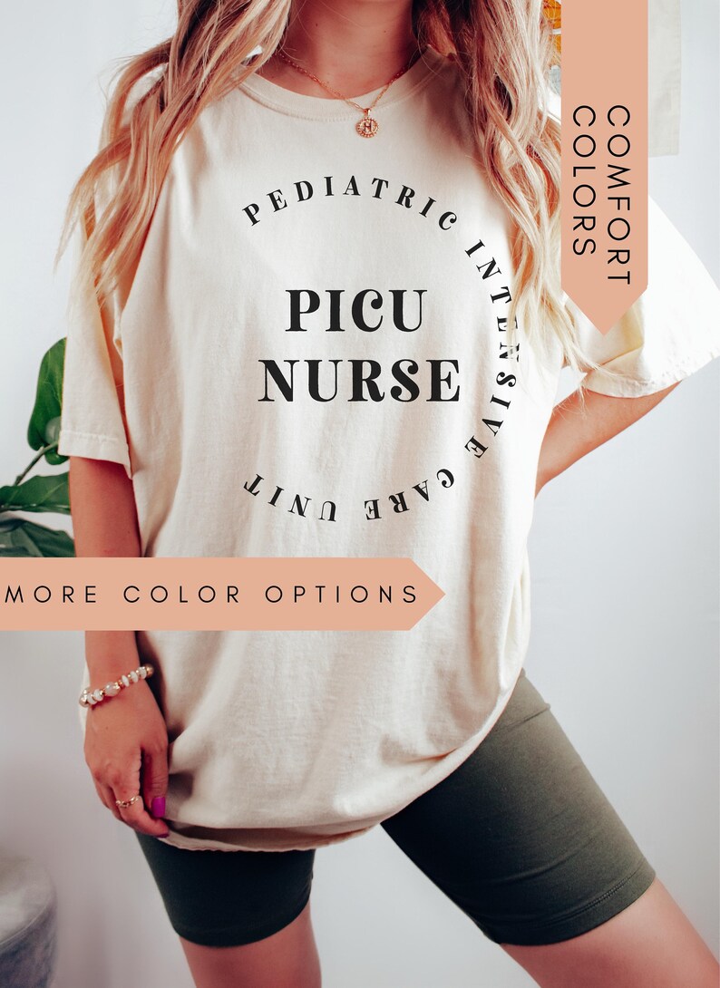 K&ouml;nnte beinhalten: Ein wei&szlig;es T-Shirt mit schwarzem Text, der "Pediatric Intensive Care Unit PICU Nurse" lautet. Der Text befindet sich in einem Kreis. Das Shirt wird von einer Person getragen. Der Text "Comfort Colors" befindet sich in einem pfirsichfarbenen Kasten in der oberen rechten Ecke des Bildes. Der Text "More Color Options" befindet sich in einem pfirsichfarbenen Kasten in der unteren linken Ecke des Bildes.
