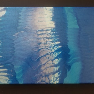 May include: Abstract painting on canvas with blue, white, and teal colors. The paint has been poured and swirled to create a unique design.