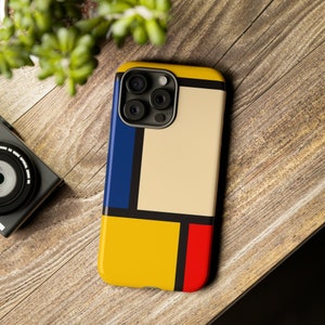 May include: A phone case with a geometric design featuring squares in blue, yellow, red, and beige. The case has a cutout for the phone's camera.