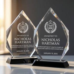 May include: Two clear crystal awards with a diamond-shaped design, set on black bases. Each award features the text "Awarded to Nicholas Hartman" and "In recognition of your 25 years of dedicated service and commitment. January 15, 2025."