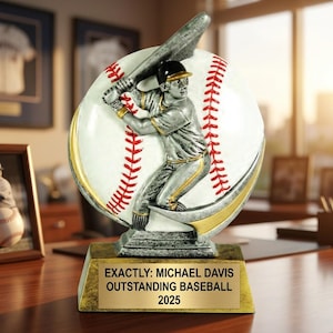 Op de afbeelding: Een honkbaltrofee met een zilverkleurige figuur van een slagman die zwaait voor een witte honkbal met rode stiksels. De trofee staat op een goudkleurige voet met een plaatje met de tekst: EXACTLY: MICHAEL DAVIS OUTSTANDING BASEBALL 2025.