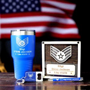 May include: A blue tumbler, keychain, bottle opener, pen, and plaque with military insignia and the text "SSgt Steve Jackson Line #1698". The items are displayed against an American flag background.