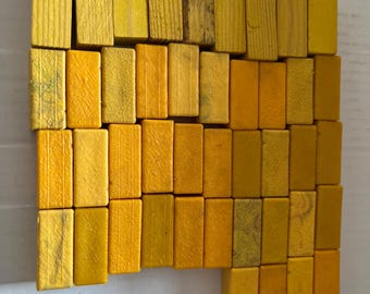 May include: A collection of yellow wooden blocks arranged in a staggered pattern. The blocks are all the same size and shape, and they are made of a light-colored wood.