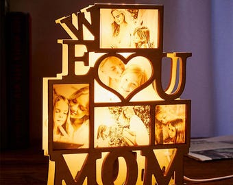 Könnte beinhalten: Holzbildrahmen mit einem Herzen und den Worten "We Love You Mom" in hellem Holz. Der Rahmen hat mehrere Öffnungen für Fotos und wird mit warmweißen LED-Lichtern beleuchtet.