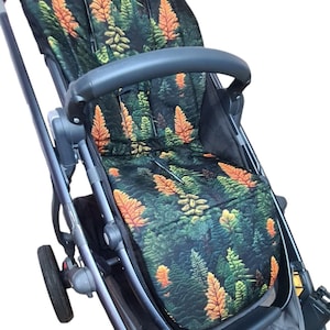 May include: A black stroller with a green, orange and yellow floral print seat liner. The stroller has a black handle and a black frame.