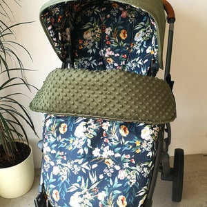 Könnte beinhalten: Ein grüner Kinderwagen-Baldachin mit gestepptem Muster und einer floralen Innenausstattung. Der Kinderwagen hat auch eine grüne Fleece-Innenausstattung mit einem gepunkteten Muster.