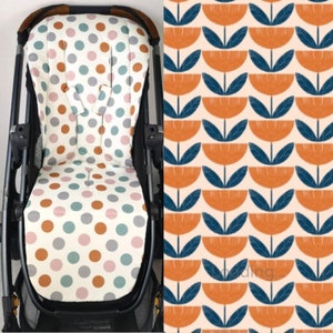 Könnte beinhalten: Ein Kinderwagen-Sitzbezug mit weißem Hintergrund und bunten Punkten. Der Bezug ist aus weichem, atmungsaktivem Stoff gefertigt und soll den Kinderwagensitz vor Schmutz und Verschüttungen schützen. Der Bezug ist auch maschinenwaschbar.