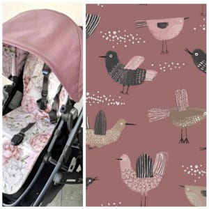 Könnte beinhalten: Ein Kinderwagen mit einem rosafarbenen Verdeck und einem Sitz mit Blumenmuster. Der Sitz hat ein Design aus großen rosa und weißen Blumen. Der Stoff auf der rechten Seite des Bildes hat ein sich wiederholendes Muster aus stilisierten Vögeln in verschiedenen Farben auf einem malvenfarbenen Hintergrund.
