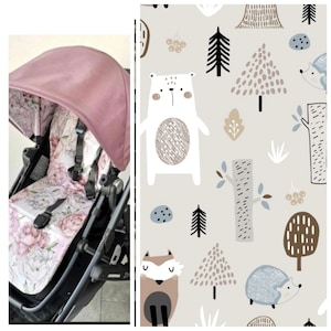 May include: A baby pushchair with a dusky pink hood and a floral-patterned seat. The seat features a design of large pink flowers. The pushchair is black with a matching floral pattern on the seat. The background shows a repeating pattern of forest animals and trees.