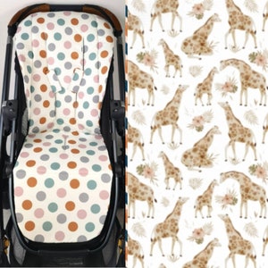 Könnte beinhalten: Ein weißer Kinderwagen-Sitzbezug mit einem Tupfenmuster in Blautönen, Rosa und Orange. Der Hintergrund ist ein weißer Stoff mit einem sich wiederholenden Muster aus braunen Giraffen.