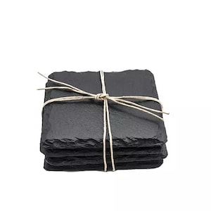 Puede incluir: Conjunto de cuatro posavasos de pizarra negra atados con cuerda. Los posavasos son cuadrados y tienen un borde áspero y natural.