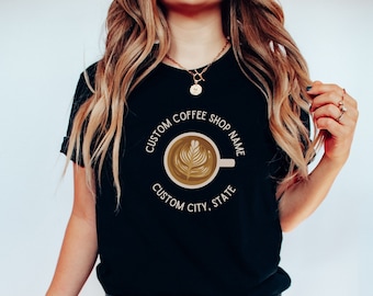 May include: Black t-shirt with a white circle graphic featuring a coffee cup with latte art and the text "CUSTOM COFFEE SHOP NAME CUSTOM CITY, STATE"