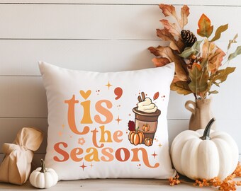 May include: White throw pillow with the text "'tis the season" in orange and yellow lettering. A cartoon image of a coffee cup with whipped cream and a pumpkin spice latte is on the right side of the pillow.