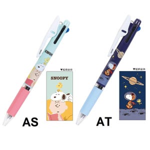 Puede incluir: Dos bol&iacute;grafos multicolores con tem&aacute;tica de Snoopy. Un bol&iacute;grafo es rosa, azul claro y blanco, con ilustraciones de Snoopy y Charlie Brown. El otro bol&iacute;grafo es azul, azul claro y blanco, con ilustraciones de Snoopy en el espacio. Cada bol&iacute;grafo tiene las letras "AS" y "AT".