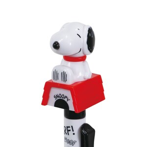 May include: A white plastic pen with a red and black Snoopy dog figurine on top. The figurine is sitting on a red doghouse with the word "Snoopy" printed on the front. The pen has the words "Woof!" and "R.F!" printed on the barrel.