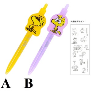 May include: Two pens featuring the character Woodstock from Peanuts. One pen is yellow with a yellow Woodstock topper, and the other is lavender with a pink Woodstock topper. A small illustration sheet with additional Woodstock images is also included.