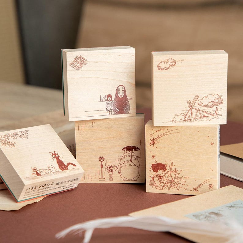 May include: Set of five wooden stamps featuring illustrations from a popular animated film. Each stamp has a different design, including characters and scenes. The stamps are made of light-colored wood and have a rectangular shape.