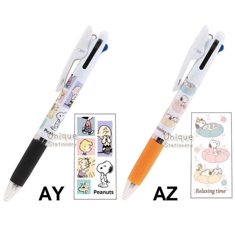 Puede incluir: Dos bol&iacute;grafos multicolores con barriles blancos, con personajes de Peanuts. Un bol&iacute;grafo tiene un agarre negro y el otro un agarre naranja. Cada bol&iacute;grafo tiene un clip blanco y el texto "Unique Stationery". Los bol&iacute;grafos est&aacute;n etiquetados como "AY" y "AZ".