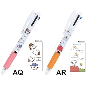 Puede incluir: Dos bol&iacute;grafos multicolores con tem&aacute;tica de Snoopy. Un bol&iacute;grafo tiene un agarre rosa e ilustraciones de Snoopy con el texto "SNOOPY & Brothers" y "AQ". El otro bol&iacute;grafo tiene un agarre naranja e ilustraciones de Snoopy y Woodstock con el texto "AR".