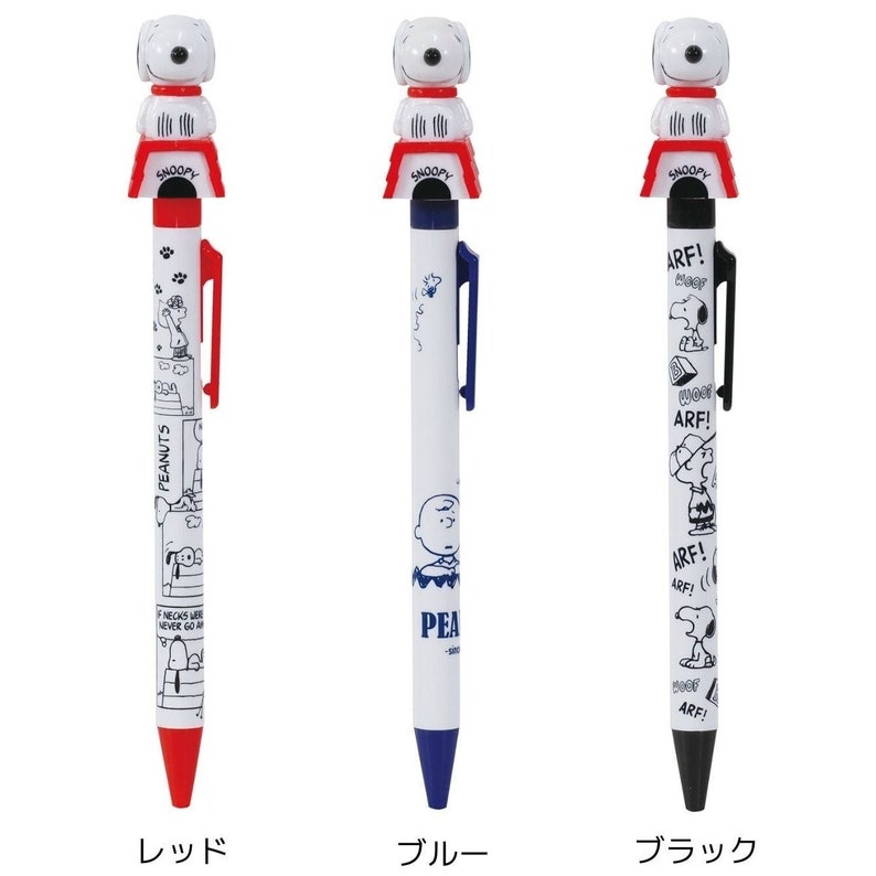 May include: Three ballpoint pens with a Peanuts character on top. The pens are white with black ink and have different coloured tops: red, blue, and black. The red pen has a Peanuts character on the barrel. The blue pen has a Peanuts character and the word "PEANUTS" on the barrel. The black pen has a Peanuts character and the word "ARF!" repeated on the barrel.