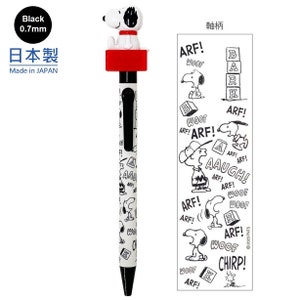 May include: A black and white Snoopy pen with a red cap. The pen has a black 0.7mm nib and features a Snoopy character design. The pen is made in Japan and has the text "日本製" and "Made in JAPAN" on the packaging. The packaging also includes a sheet of Snoopy stickers with various designs, including Snoopy saying "ARF!" and "WOOF!" and Snoopy playing with blocks that spell "BARK".