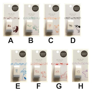 May include: A collection of eight loop stamps, each featuring a unique design. The stamps showcase various illustrations, including animals, an alien, and a mushroom. Each stamp is packaged on a white card with Japanese text and a decorative border.
