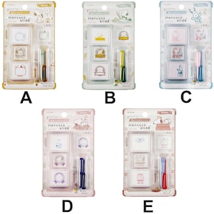 May include: Five Hancoco slide stamp sets featuring Snoopy characters in various colors. Each blister pack contains three square stamps with different designs and two ink pads. The packaging displays the text Hancoco slide and Snoopy.