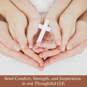 May include: A white cross is held in the center of the image, cradled by multiple hands. The text at the bottom reads: "Send Comfort, Strength, and Inspiration in one Thoughtful Gift."