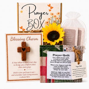 May include: A gift set featuring a Prayer Box with floral illustrations, a Blessing Charm card with a wooden cross, a yellow sunflower, and a small fabric Prayer Quilt with a printed poem, all accompanied by a white organza bag with cards.
