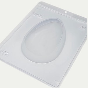 May include: A clear plastic mold for making chocolate eggs. The mold has a single cavity shaped like an egg. The mold is labeled "EUTR" and "350".