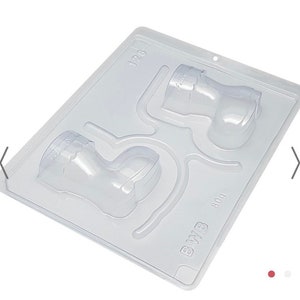 May include: A clear plastic mold for making chocolate boots. The mold has two cavities, each shaped like a boot with a curved top. The mold is labeled "B.W.B 800" and "128".