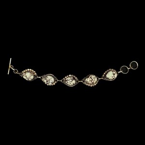 K&ouml;nnte beinhalten: Silberarmband mit f&uuml;nf tropfenf&ouml;rmigen Steinen mit gesprenkeltem Muster. Die Steine sind in einer Silberfassung mit einem Perlenrand gefasst. Das Armband hat einen Knebelverschluss.